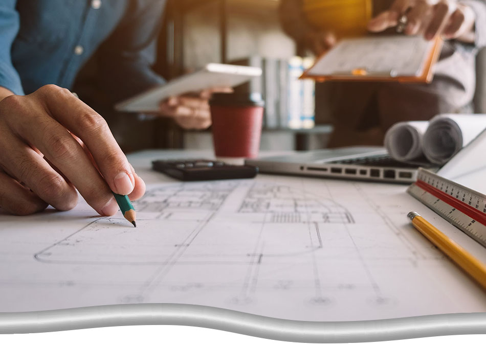 Development phase of a project. Closeup of hand holding pencil over a large blueprint. Photo also includes rulers, calculators, laptop, coffee, clipboards. Casual presentation, not formal.