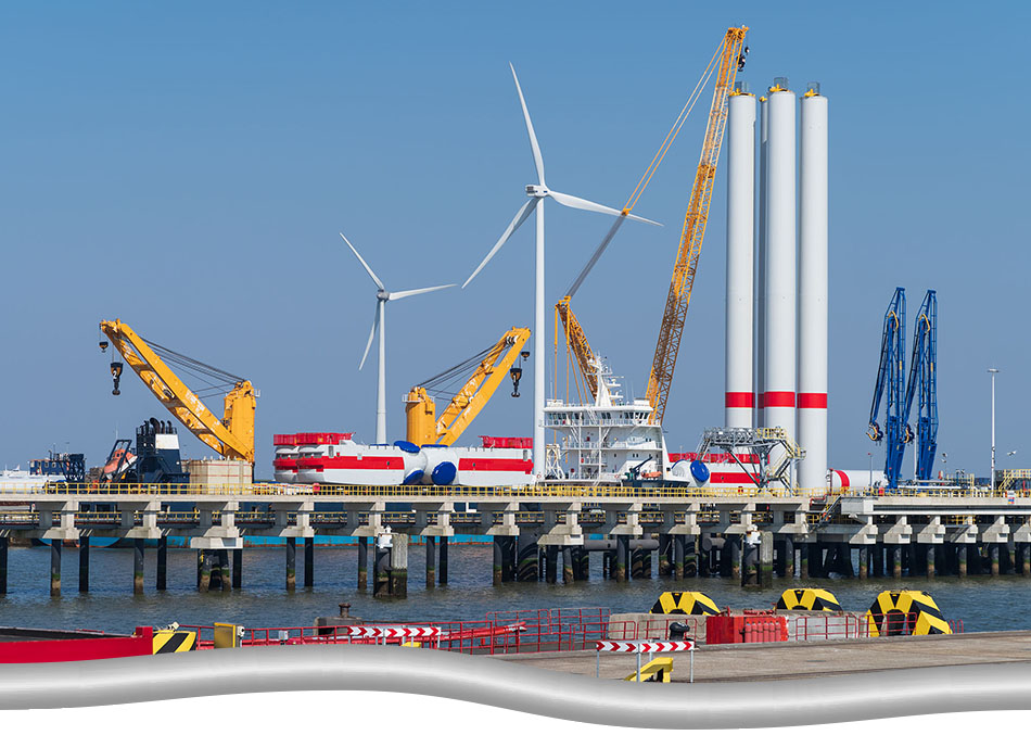Pre-assembly process of offshore wind turbine project. Turbine base columns put up by cranes.