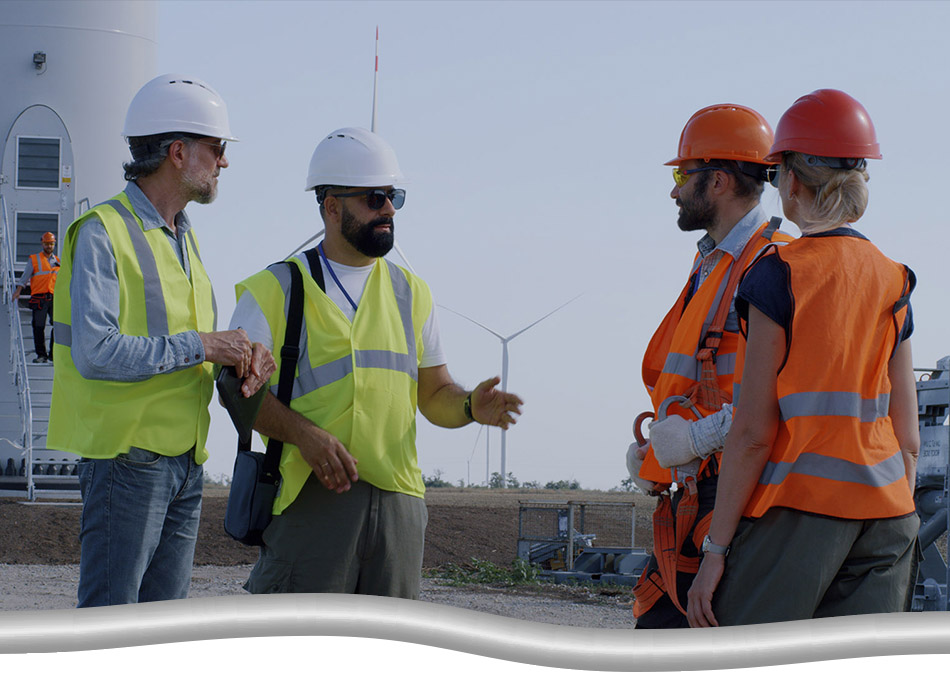 A group of safety managers and inspectors speaking to each other at a wind turbine site.
