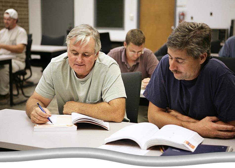 Close up shot of two people in training session, with textbooks open on the table in a classroom setting.